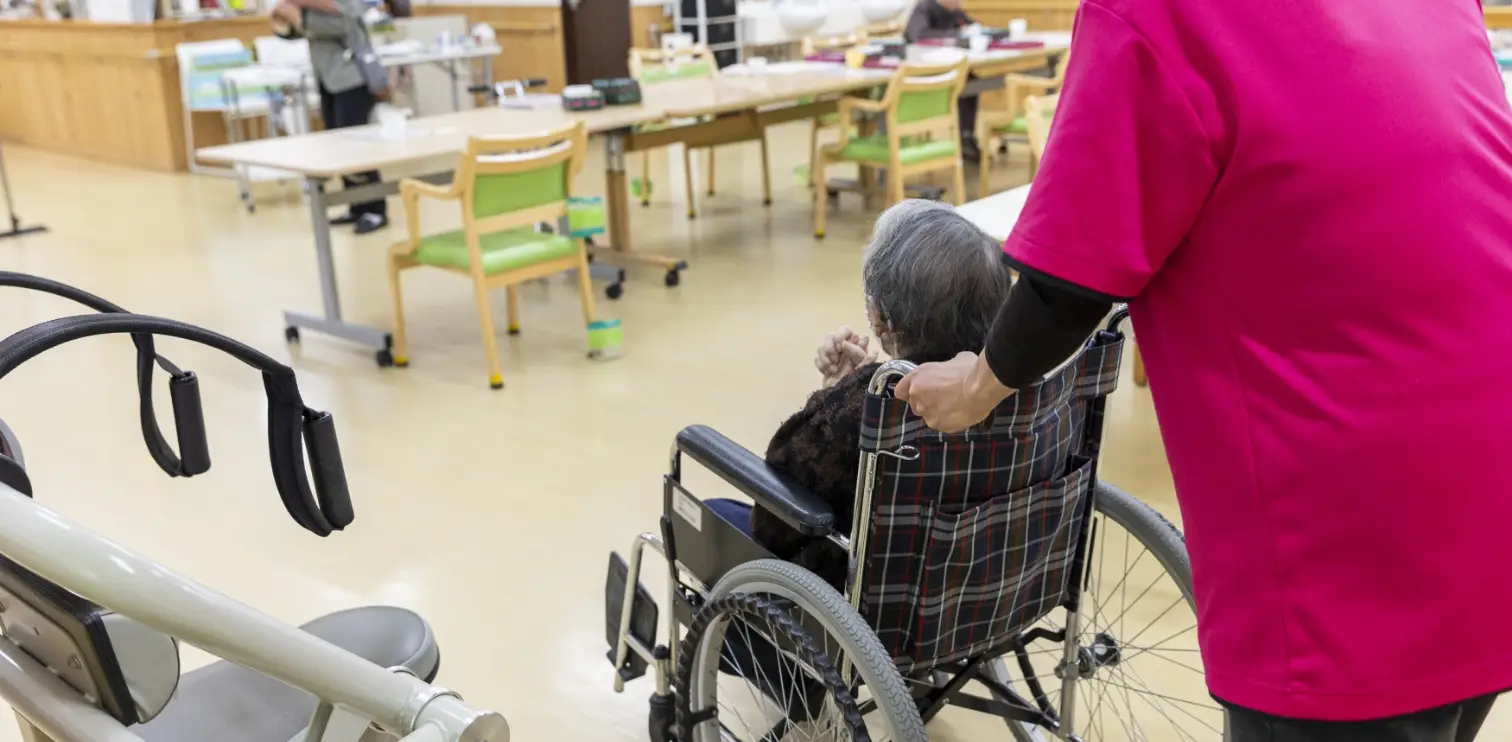 スタッフが車椅子を押しながら移動をサポートしている様子