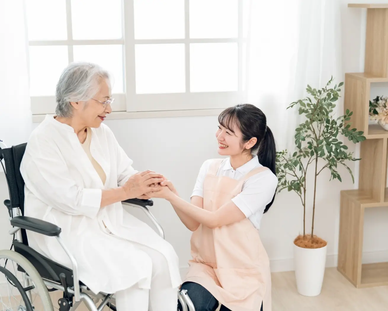 スタッフが車椅子の利用者に寄り添い手を取っている様子